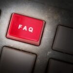 Stock image of closeup of black keyboard with red button reading "FAQ."